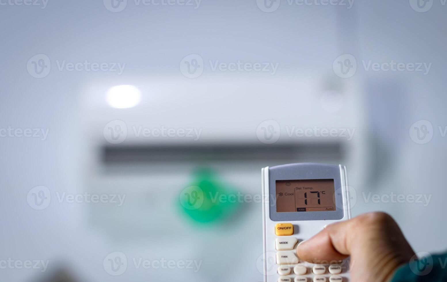 Man's hand holding remote control directed at air conditioner. photo