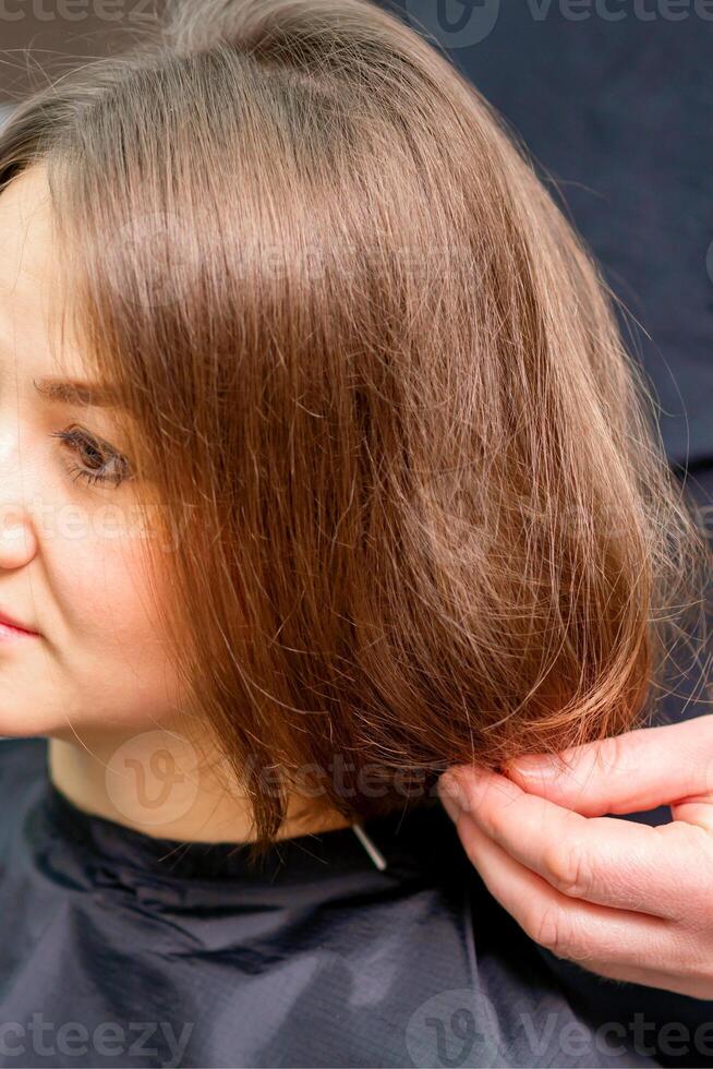 Styling female hair. Male hairdresser makes hairstyle for a young woman in a beauty salon. photo