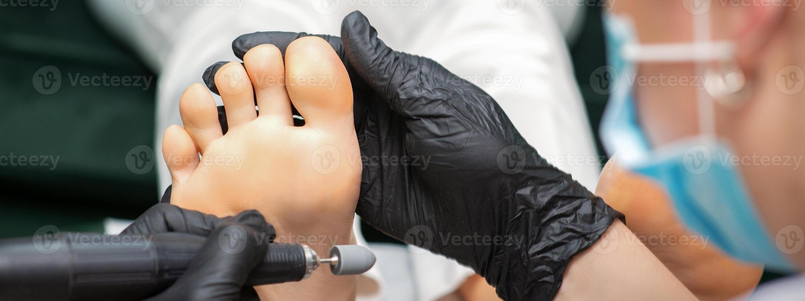 Peeling pedicure procedure on the sole from callus of the female foot by a pedicurist at a beauty salon. photo