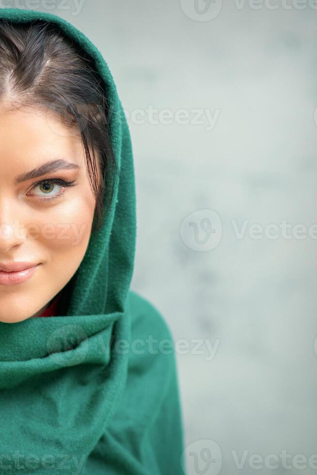 Portrait of a pretty young caucasian woman with makeup in a green headscarf on gray background. photo