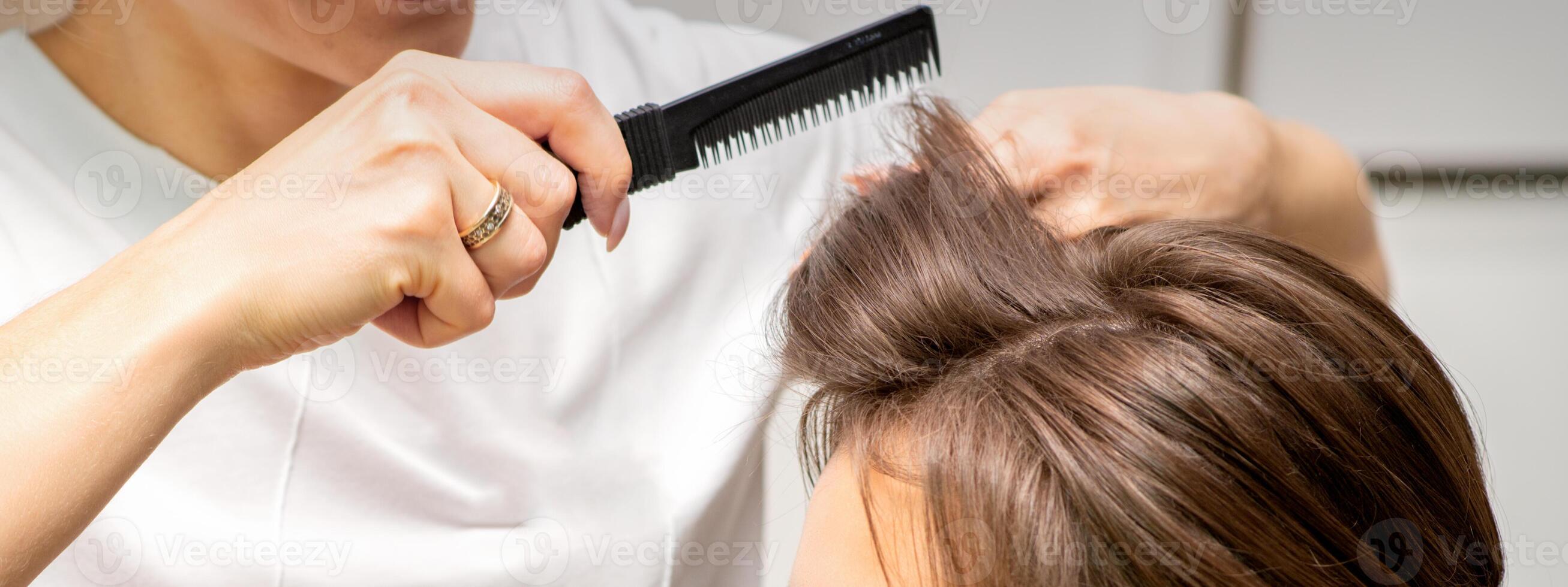 profesional peluquero haciendo peinado para un hermosa morena joven mujer con largo cabello. concepto de Moda y belleza. foto