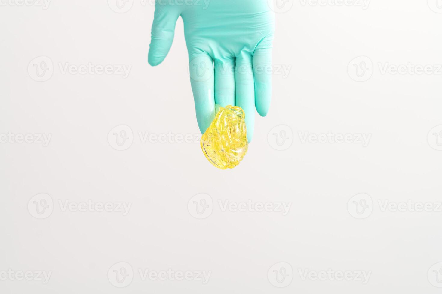 Yellow sugar paste in hand master of depilation. Smiling beautician holding wax for depilation over white background. Concept epilation. photo