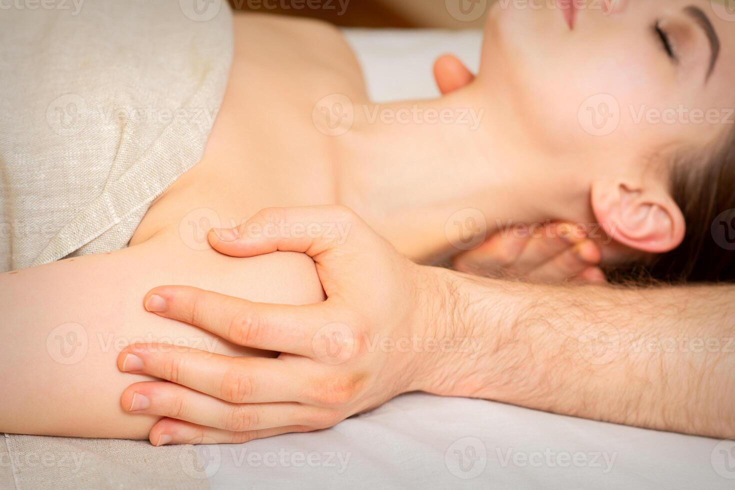 masculino masajista masajear hombro de un joven mujer acostado en un masaje mesa en un spa clínica. foto