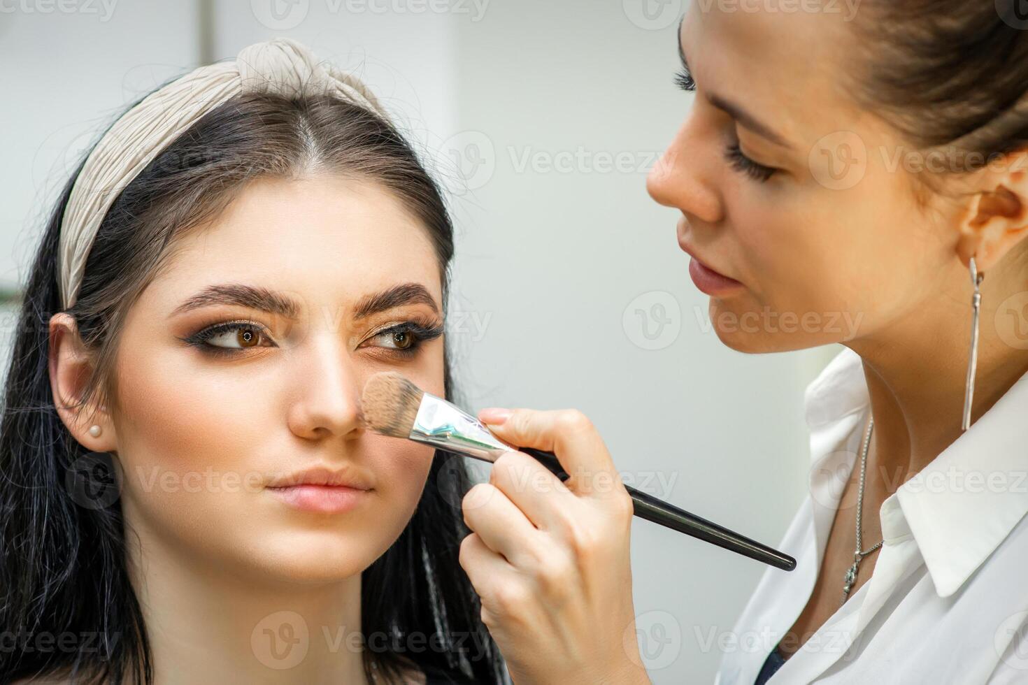 de cerca retrato de un mujer aplicando seco cosmético tonal Fundación en el cara utilizando un maquillaje cepillar. maquillaje detalle. foto