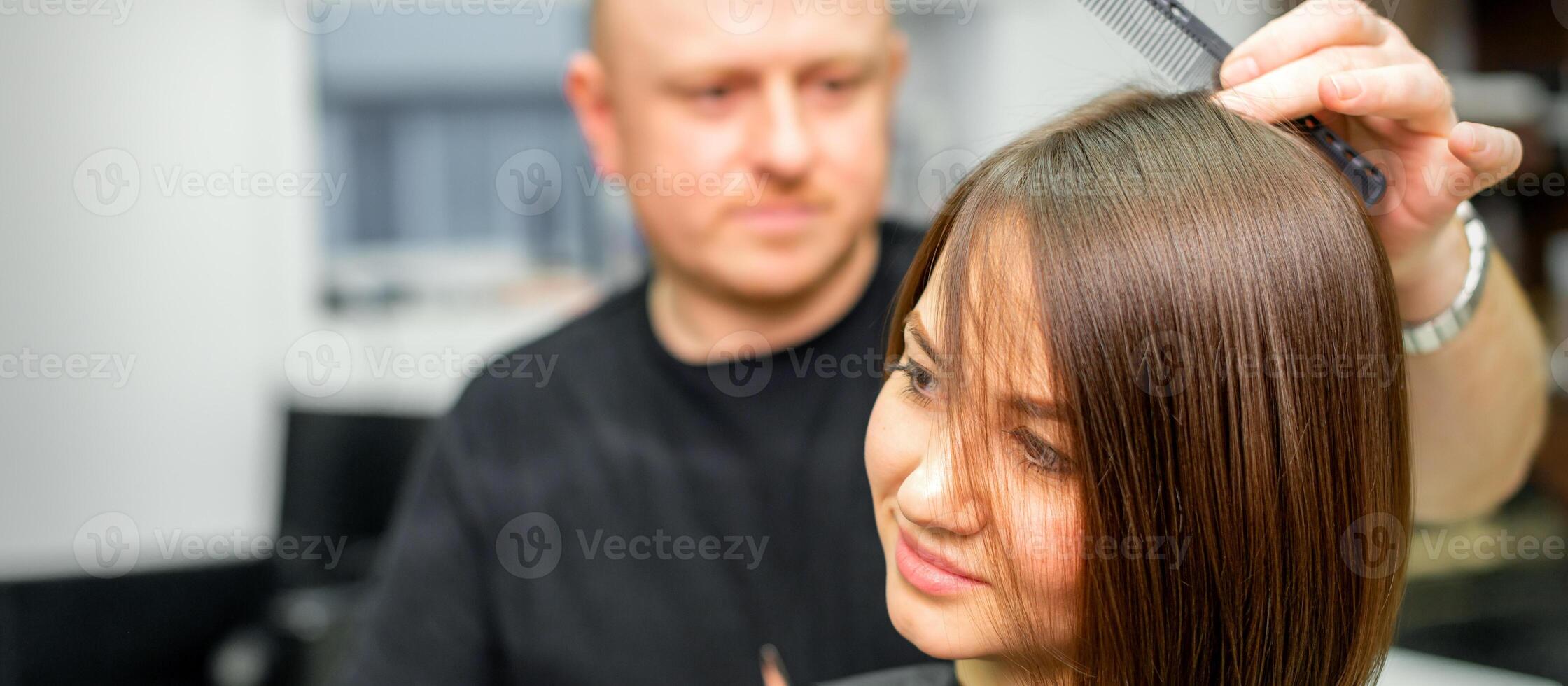 Young caucasian brunette woman having her hairstyling by a male hairdresser at a parlor. photo