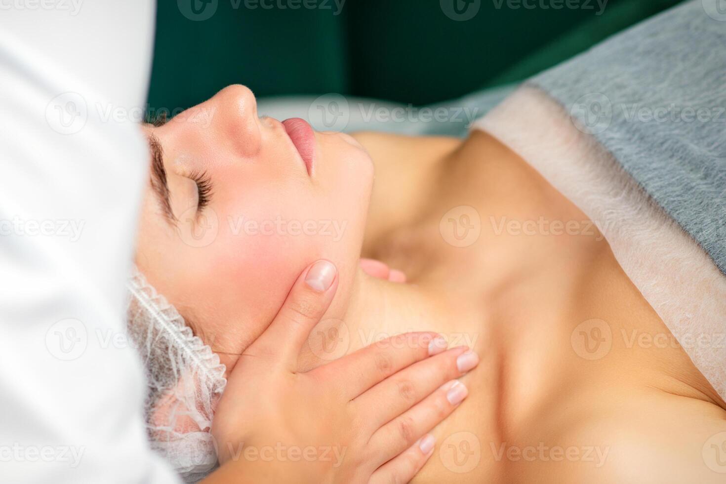 Massaging female neck. Young caucasian woman receiving neck massage relaxing in spa salon. photo