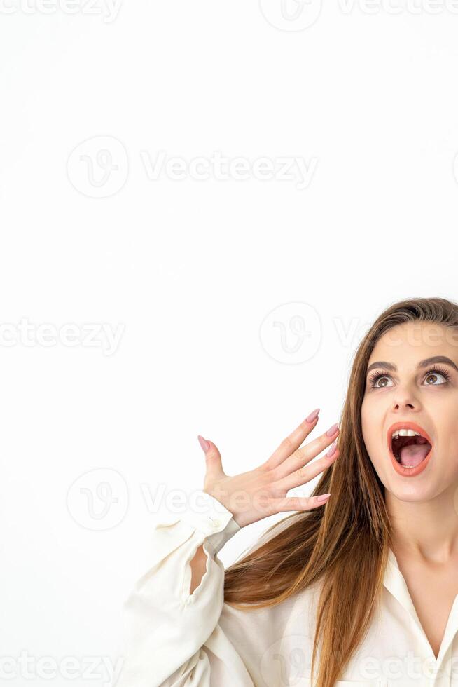 Shocked young caucasian woman with open mouth looking up and expresses surprise isolated over white background. Beautiful surprised brunette woman in studio. photo