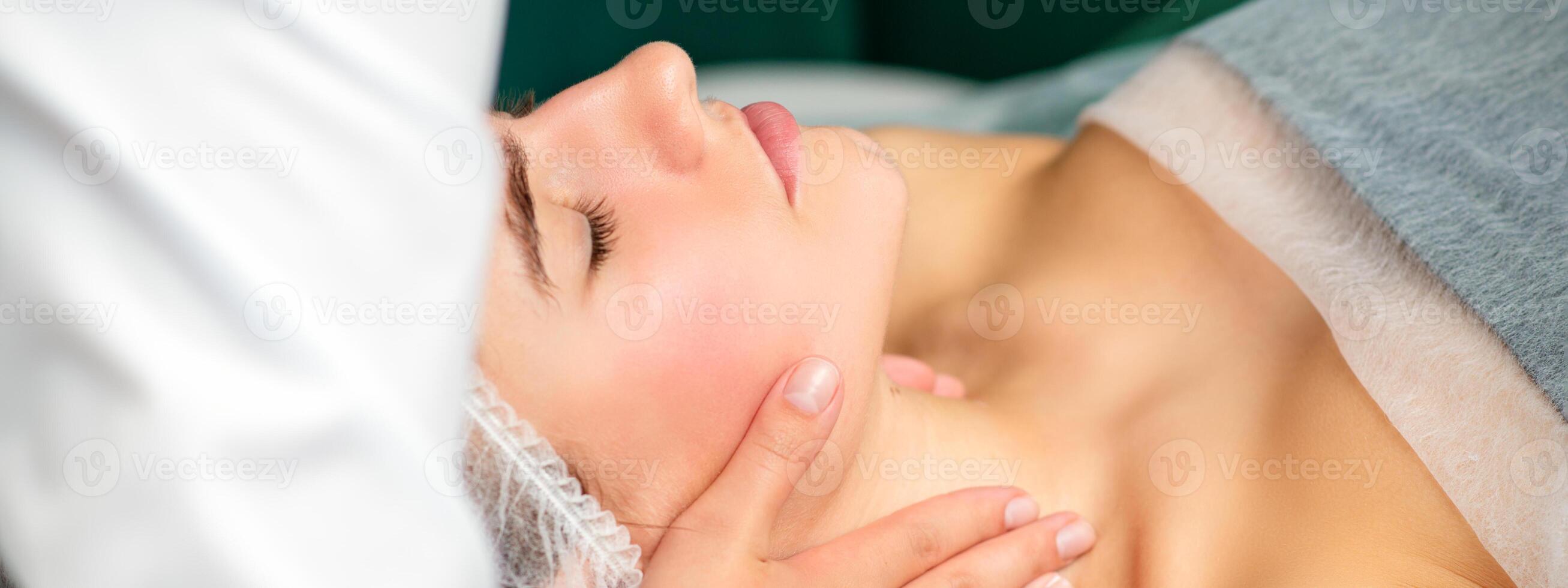 Massaging female neck. Young caucasian woman receiving neck massage relaxing in spa salon. photo