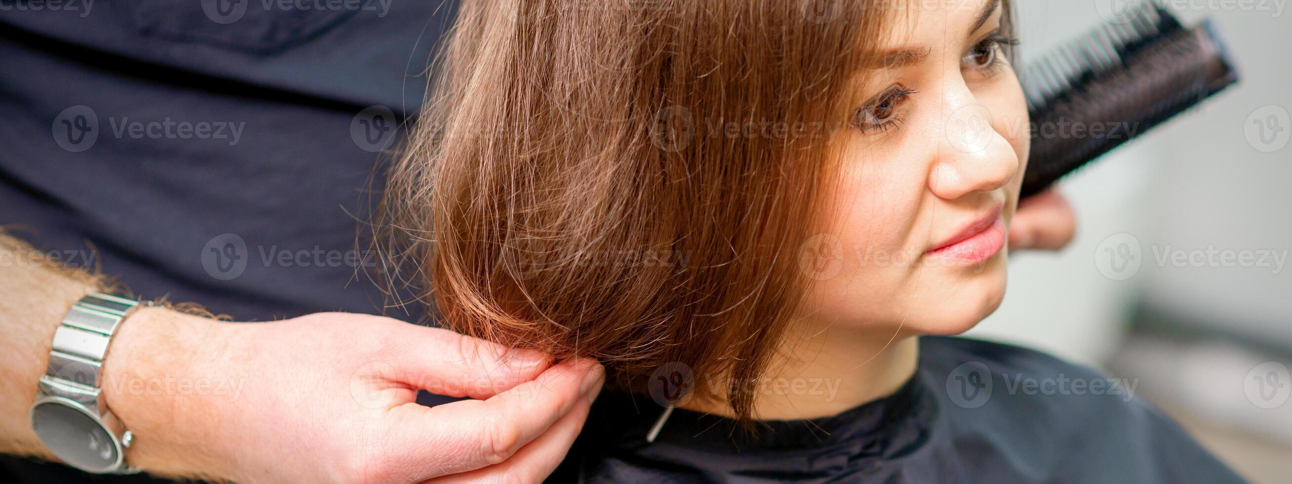 peinado hembra cabello. masculino peluquero hace peinado para un joven mujer en un belleza salón. foto