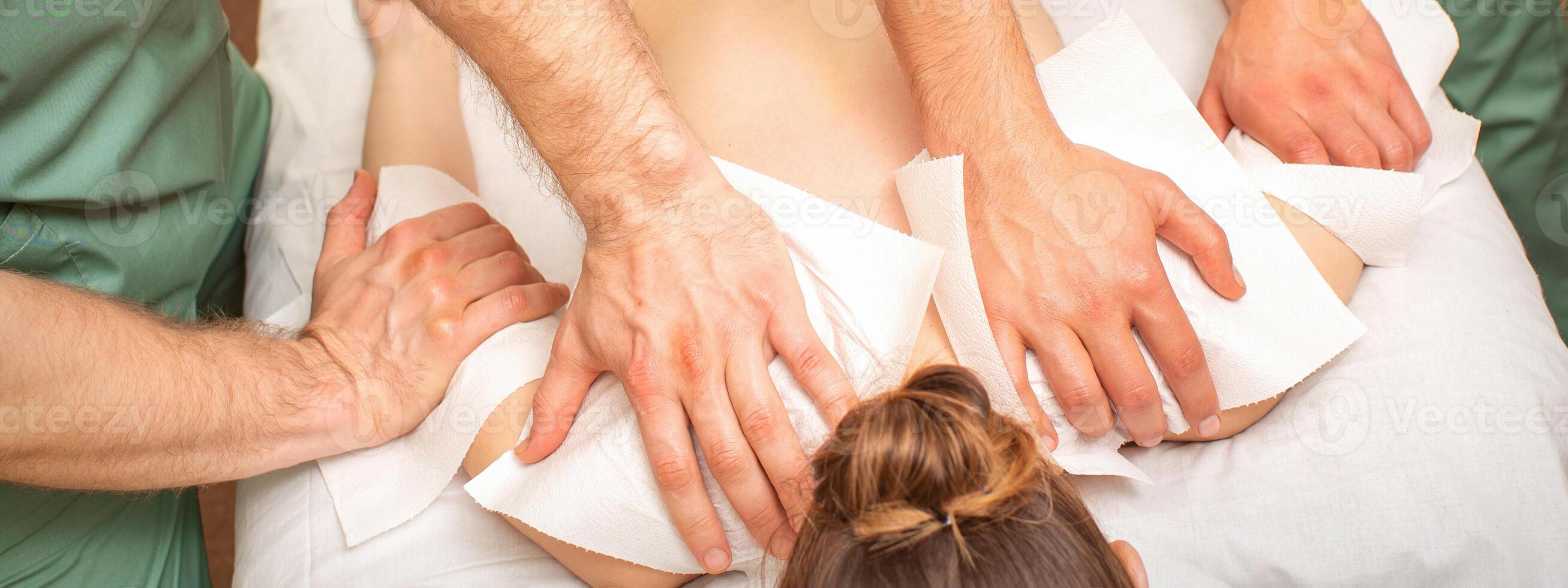 espalda masaje con cuatro manos en el spa salón. dos masaje terapeutas hacer un espalda masaje para un joven mujer. foto