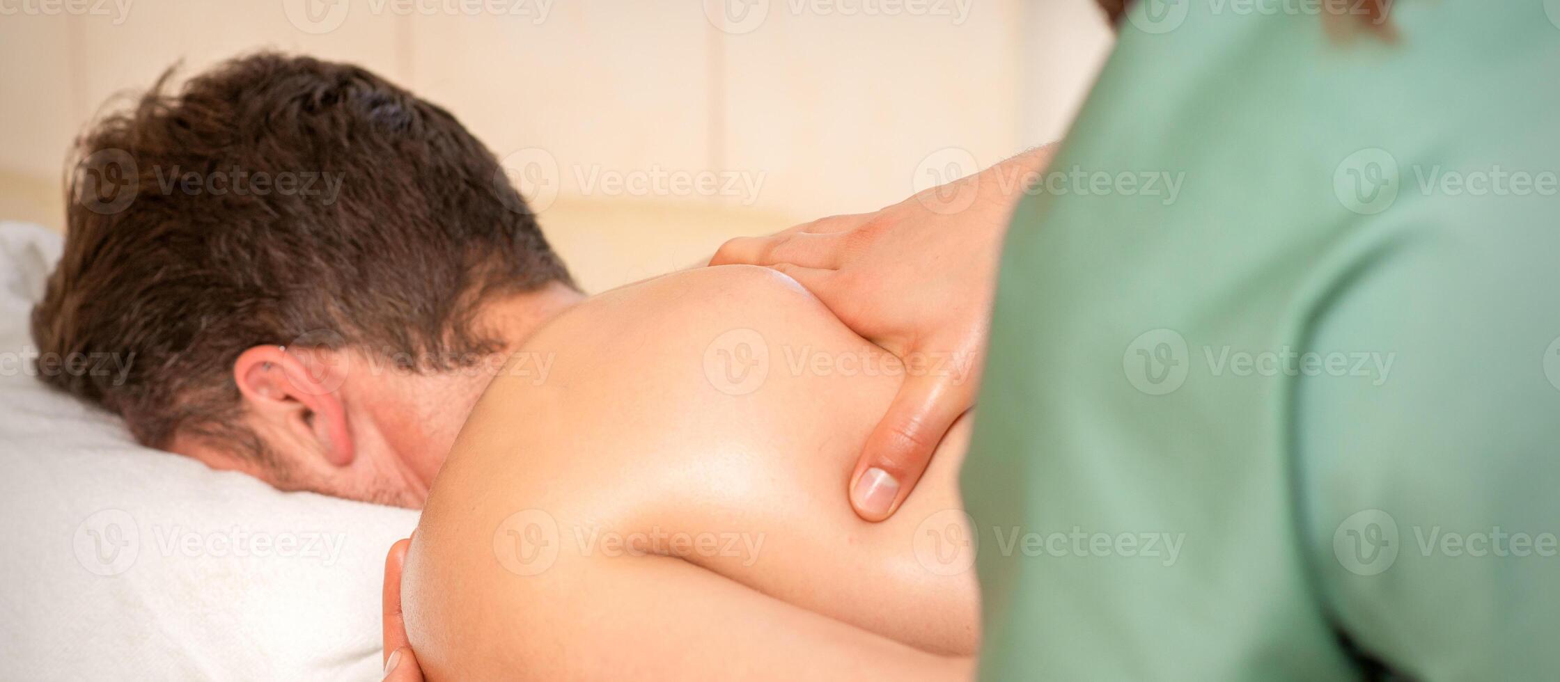 Physiotherapist giving shoulder massage to man in hospital. photo