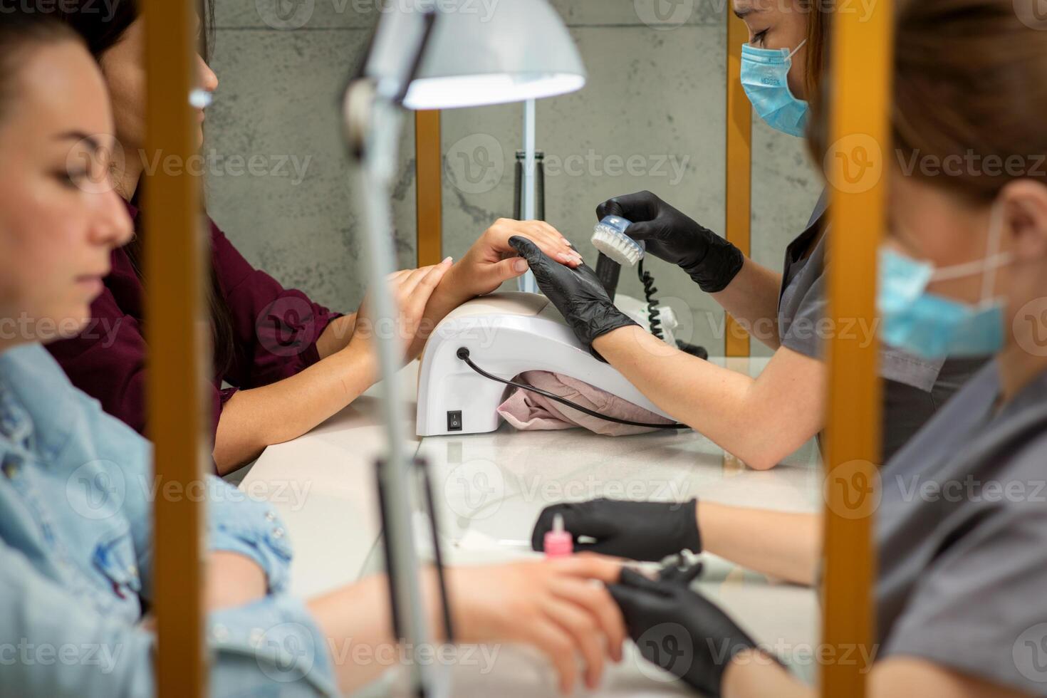Two women getting a manicure treatment in beauty salon. photo
