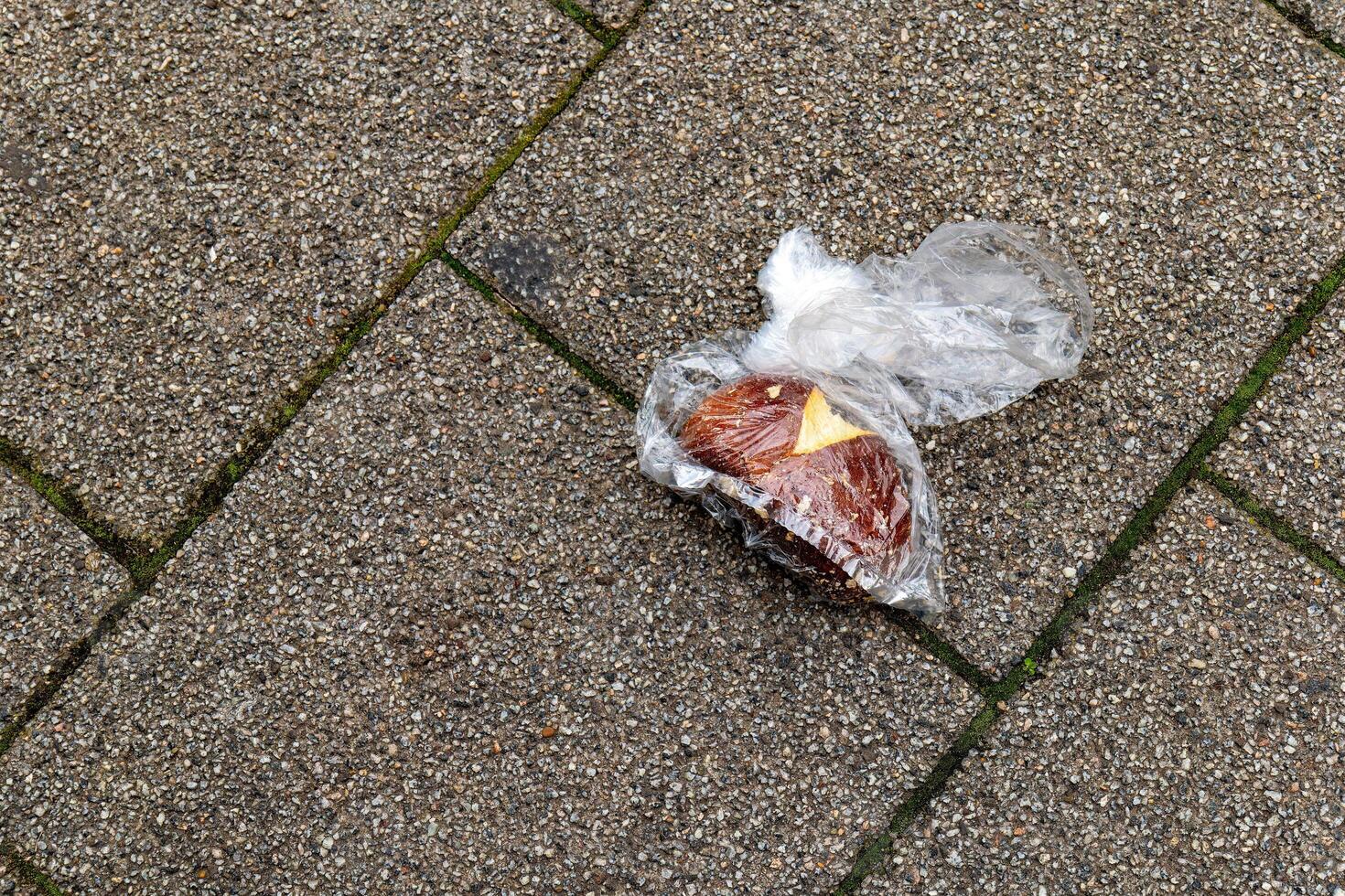 an old bread roll in a plastic bag on the street photo