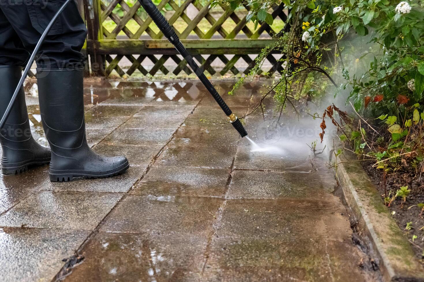 person is using a pressure washer to clean a brick patio photo