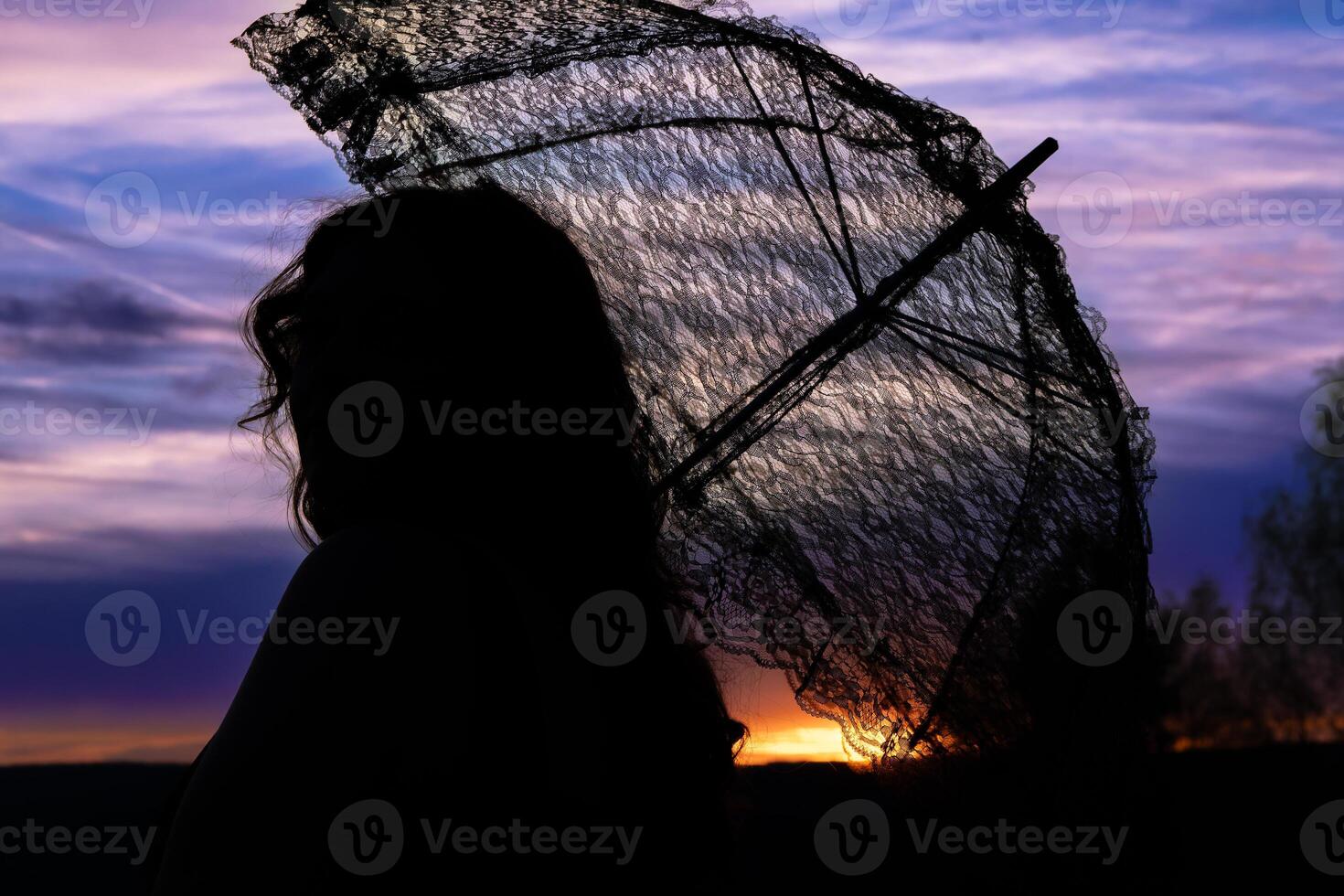 mujer con un cordón paraguas en el puesta de sol foto