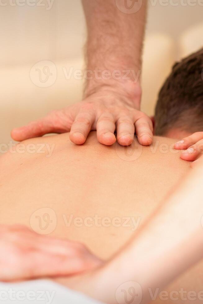 Young man receiving back massage in four hands in spa beauty salon. photo