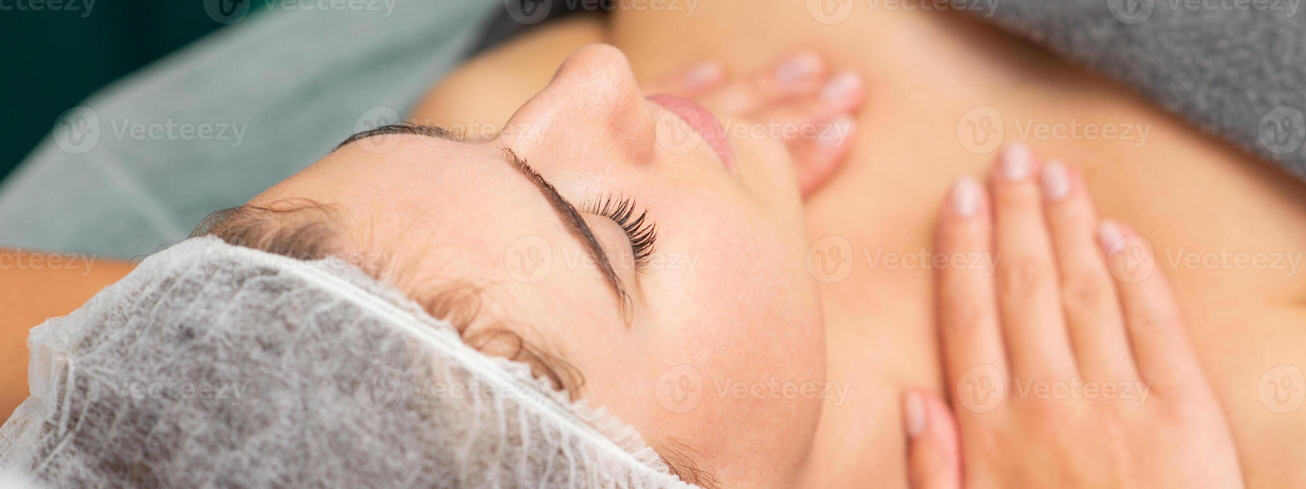 Massaging female chest. Young beautiful caucasian woman with closed eyes getting chest massage at beauty spa salon. photo