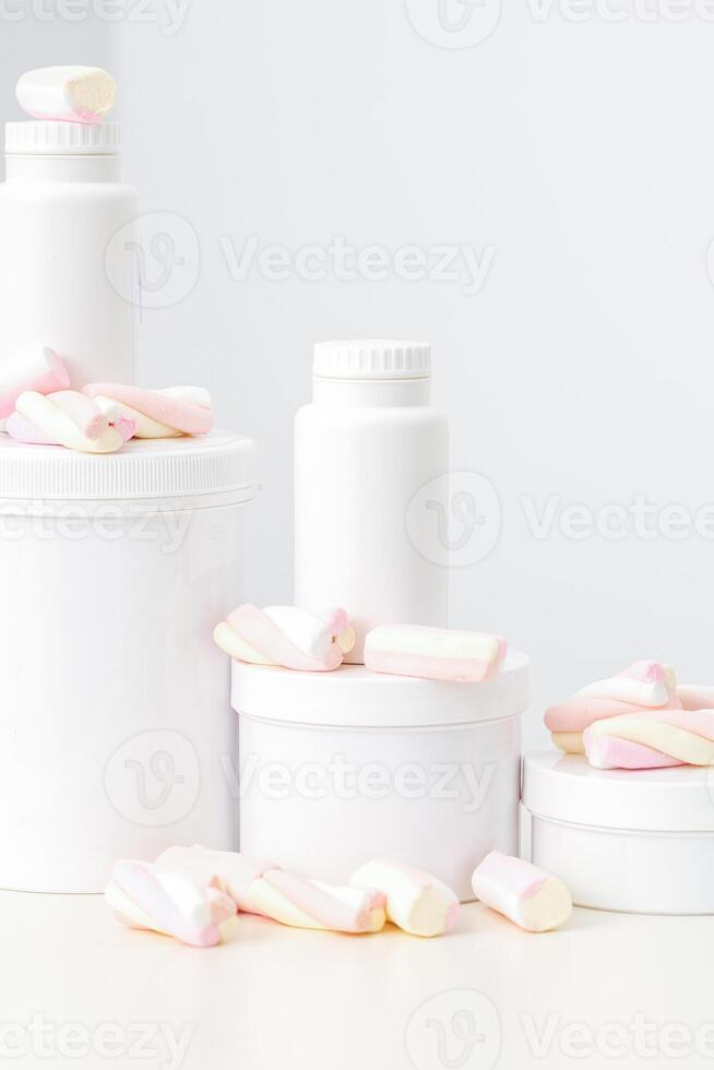 Cosmetic skincare packaging. Beauty product on white background. White jars with marshmallows on the white table. photo