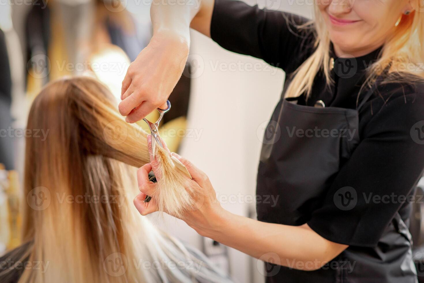 corte hembra rubia cabello. peluquero cortes pelo de un joven caucásico mujer en un belleza salón cerca arriba. foto