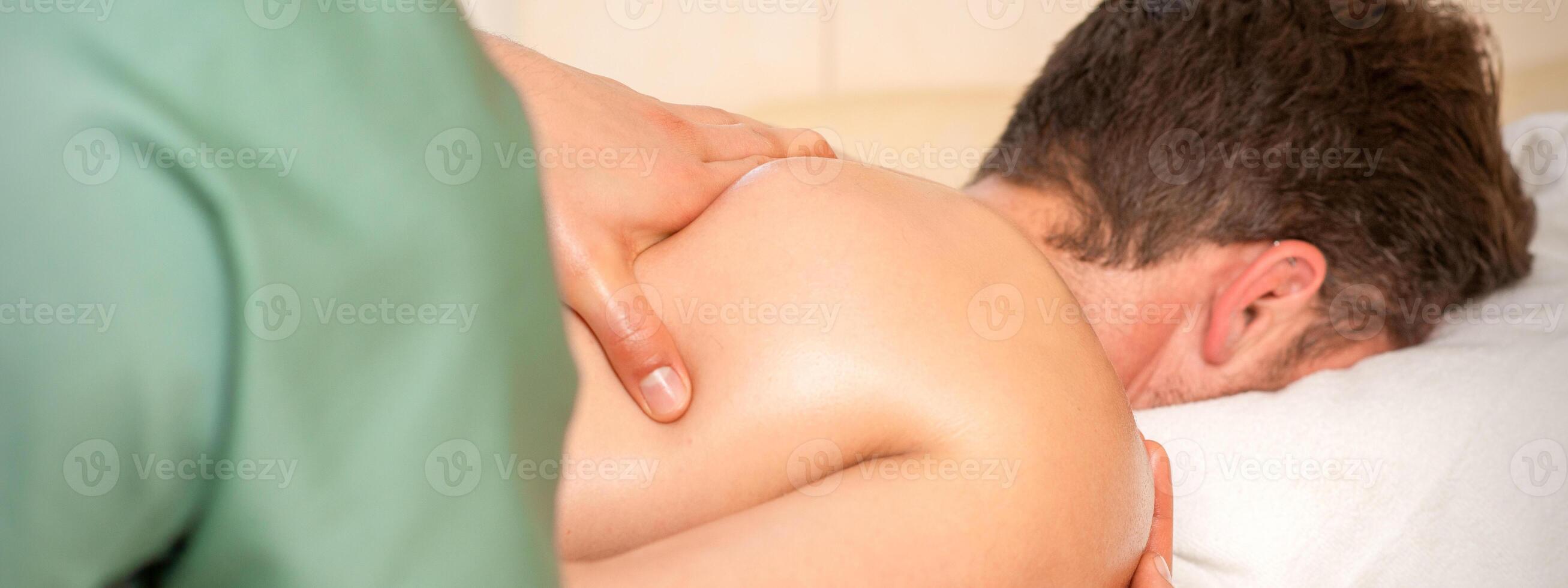 Physiotherapist giving shoulder massage to man in hospital. photo