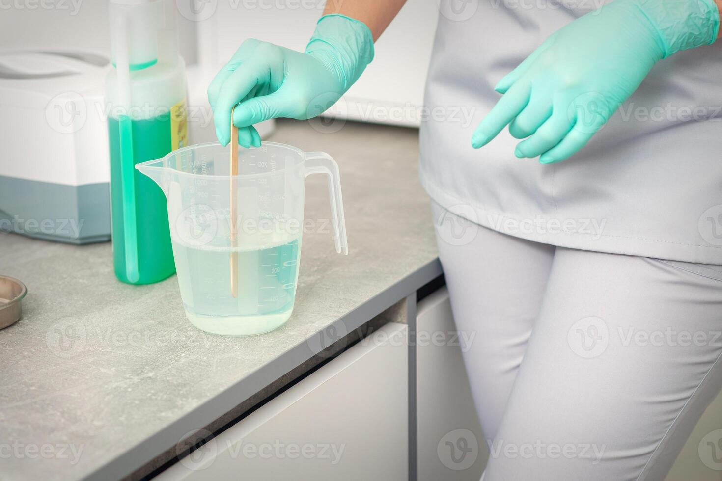 The beautician uses a stick to mix disinfectant into the water. Sterilization of tools. photo