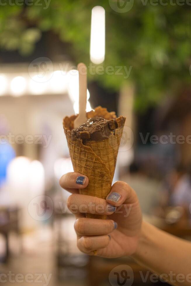 Chocolate ice cream cone in woman hand photo