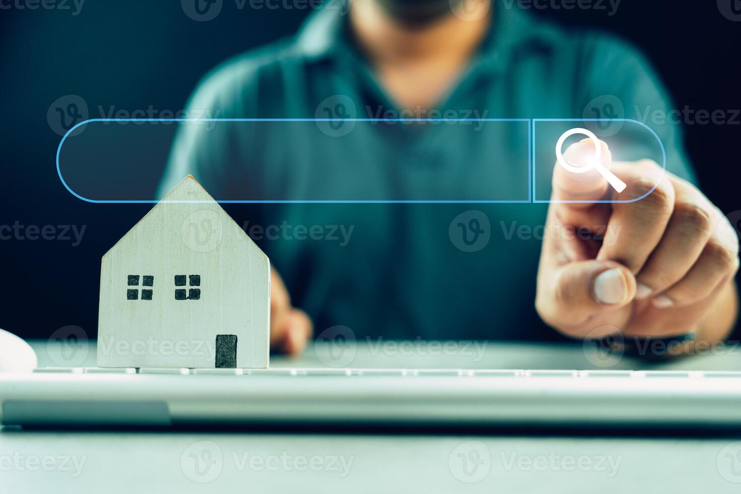 Man clicking internet search page on touch screen with wood home on keyboard. Search advertising for rent or buy a home. photo