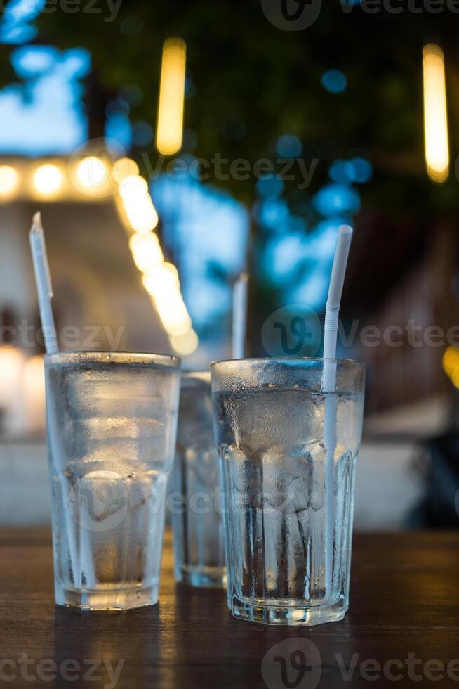 Very cold mineral water with ice and white straw. photo