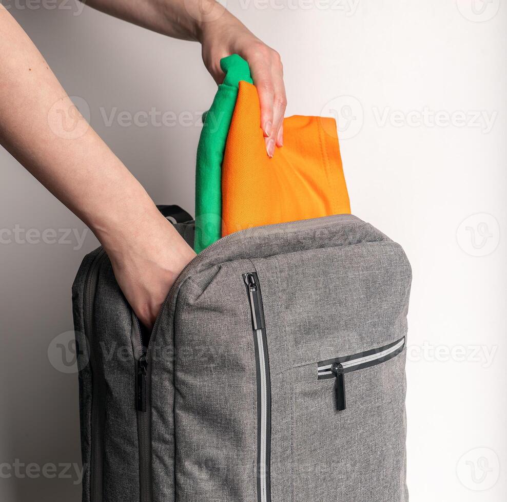 Hands packing clothes into backpack, bag photo