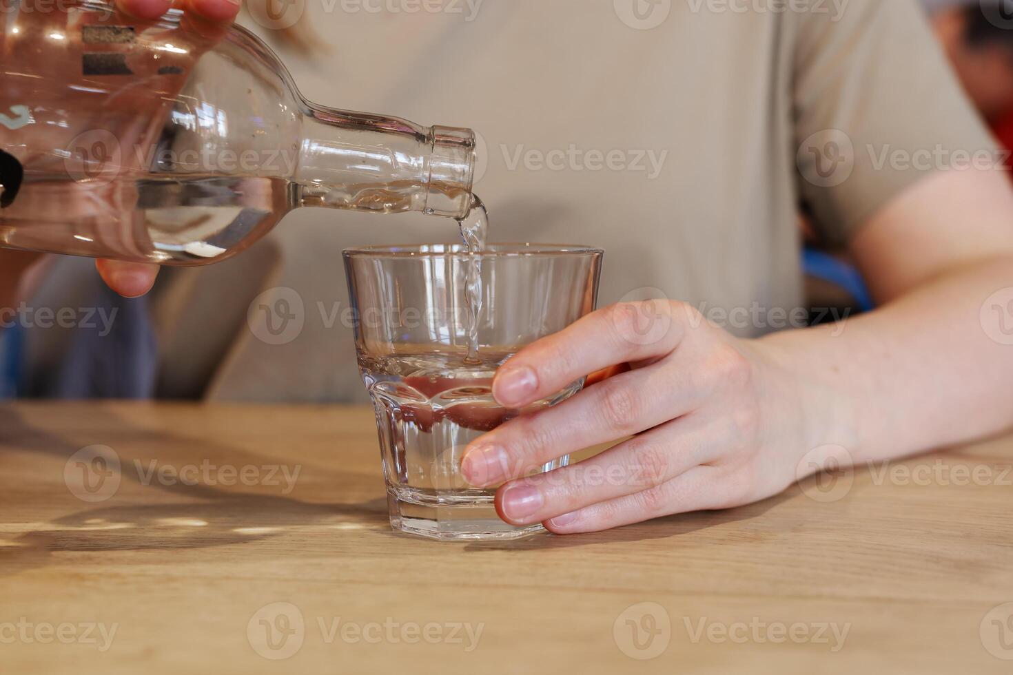 mano torrencial agua desde botella dentro vaso a de madera mesa foto