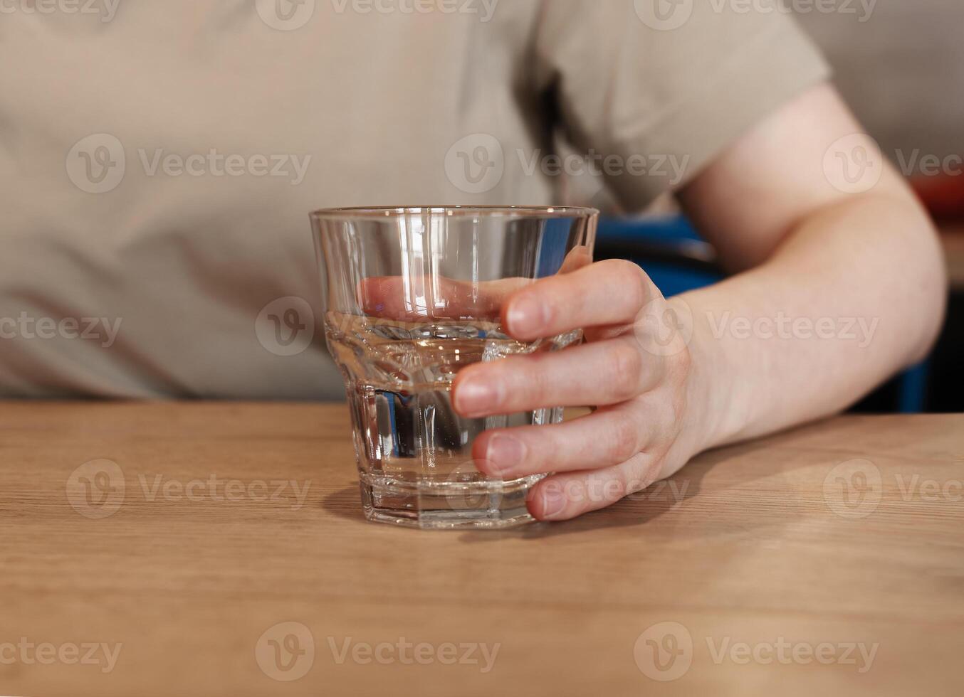 Hand holding, taking water glass at wooden table photo