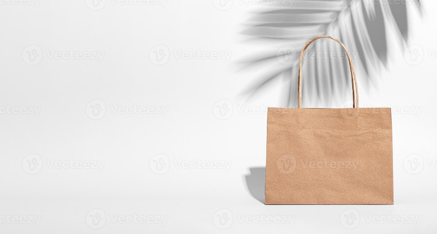 Eco kraft beige paper bag. Banner background, leaf shadow photo