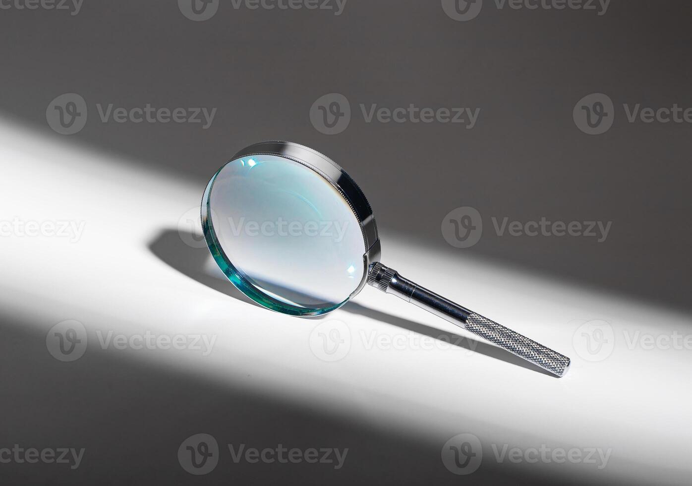 Silver shadow on glass background. Metal magnifying lens for search, zoom, exploration. Abstract photo