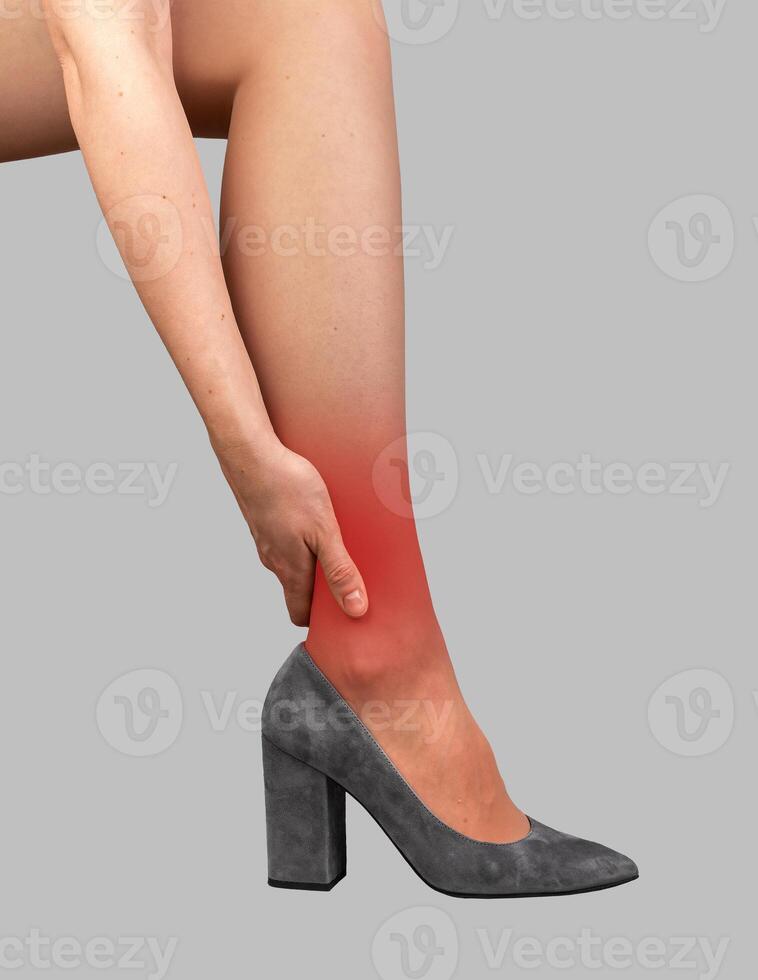 Ankle pain, ache, hurt. Hand holding leg joint, standing in high heeled shoes photo