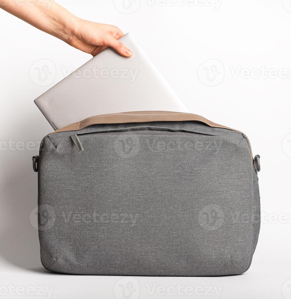 Hand taking laptop computer from notebook bag photo