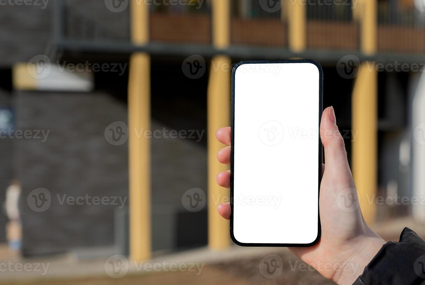 Hand holding mobile phone screen mockup, empty blank smartphone display, blurred city photo