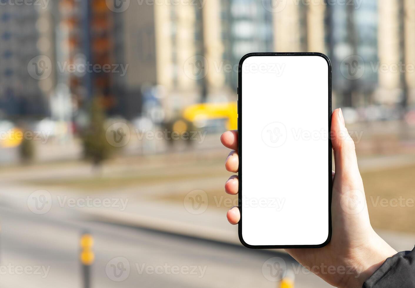 Hand holding mobile phone screen mockup, white blank smartphone display, blurred city background photo