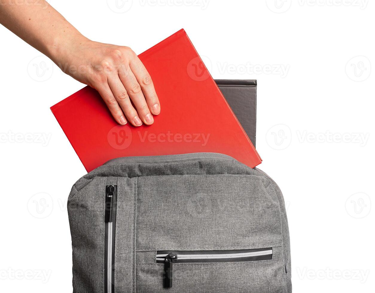 Hand putting books, textbooks into backpack, schoolbag isolated on white background photo