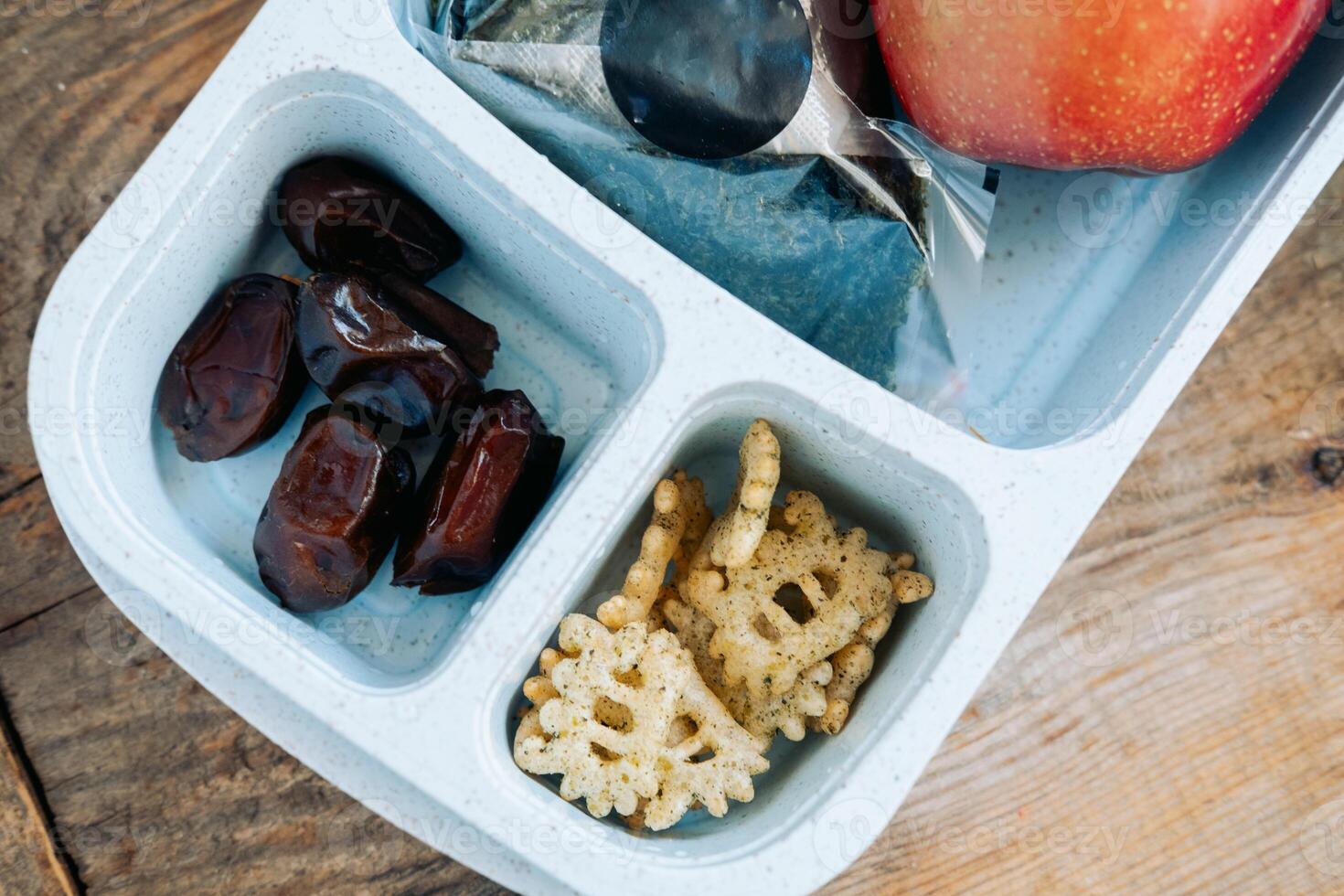 Dinner in a Muslim's lunchbox in an Asian country of onigiri, apple and soy sauce with a bottle of water photo