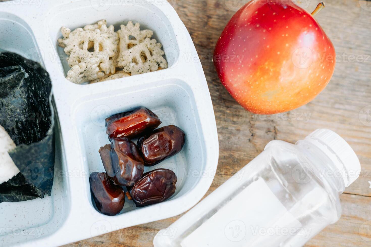 cena en un musulmán caja de almuerzo en un asiático país de onigiri, manzana y soja salsa con un botella de agua foto