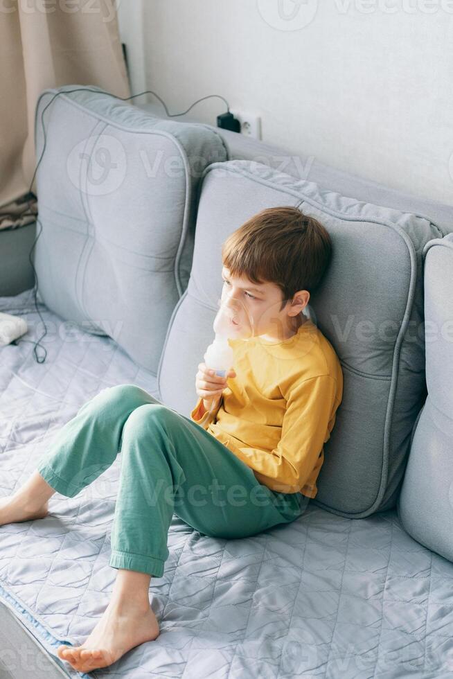 little boy sits with an inhalation mask during cough and bronchitis. Treatment with an inhaler at home photo
