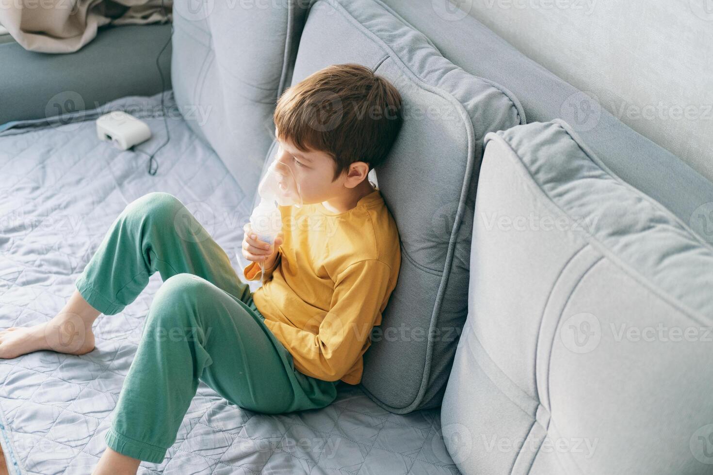 little boy sits with an inhalation mask during cough and bronchitis. Treatment with an inhaler at home photo