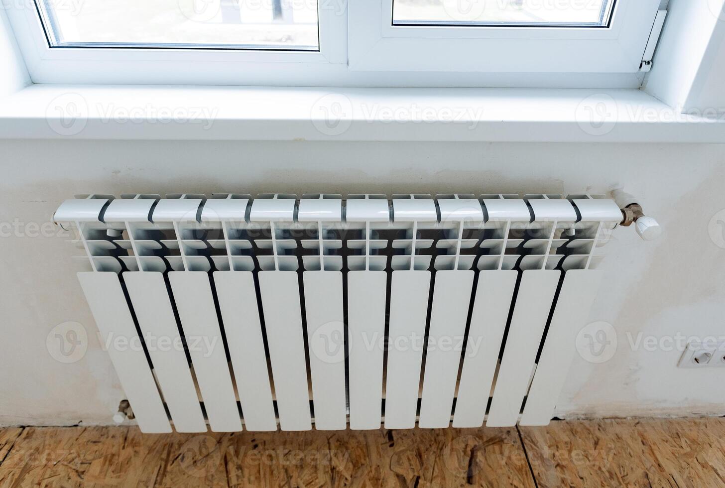 Thermal con heater at home, hot air battery hanging under the window, metal air temperature heater in the house, indoor plumbing photo