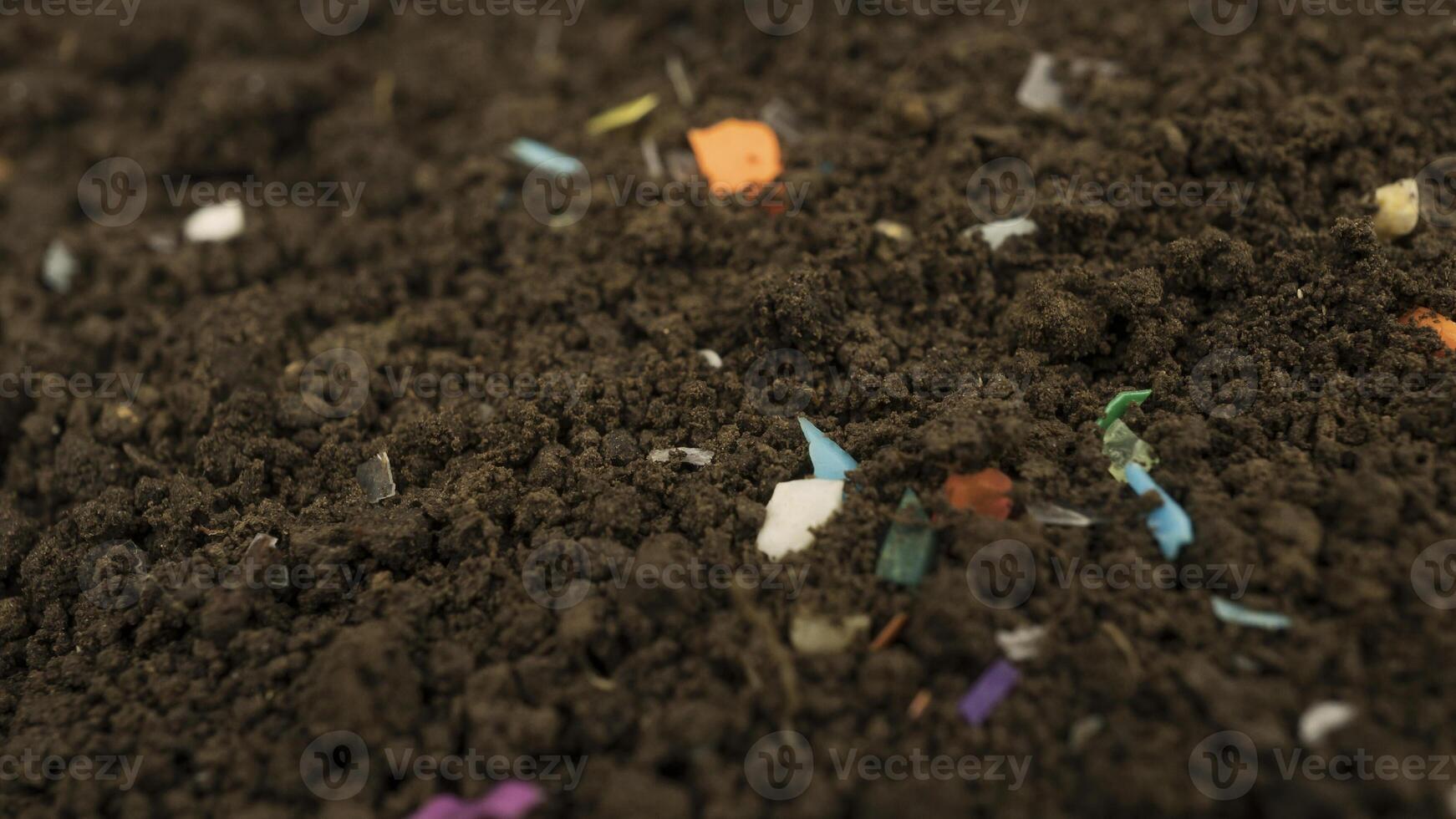 Microplastics inside the soil. Concept of plastic pollution, fertilizing and agroo industry. Non-recyclable plastic pollution in the compost at the field. Selective focus. photo