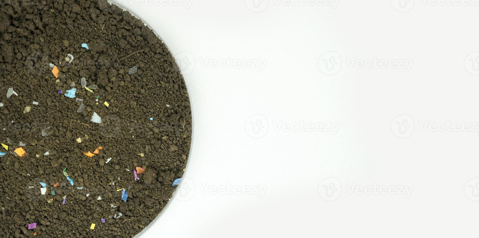 Microplastics inside the soil. Concept of plastic pollution, fertilizing and agro industry. Non-recyclable plastic pollution in the compost at the field. Selective focus. photo