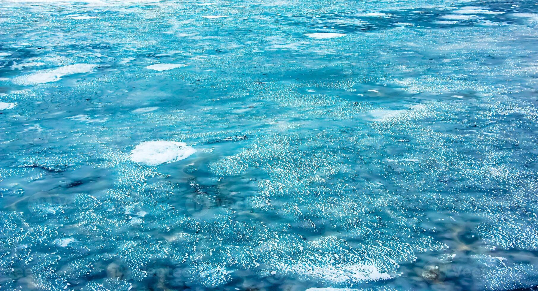 Ice surface of the river. Texture of ice shards and water. Winter background photo