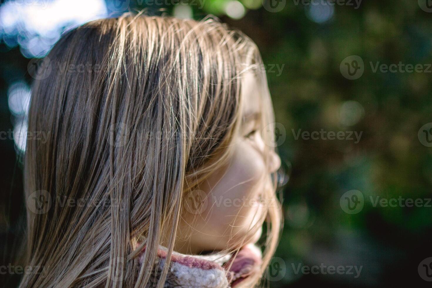 Portrait of a young girl with long blond hair smiling outdoors in a natural setting. photo
