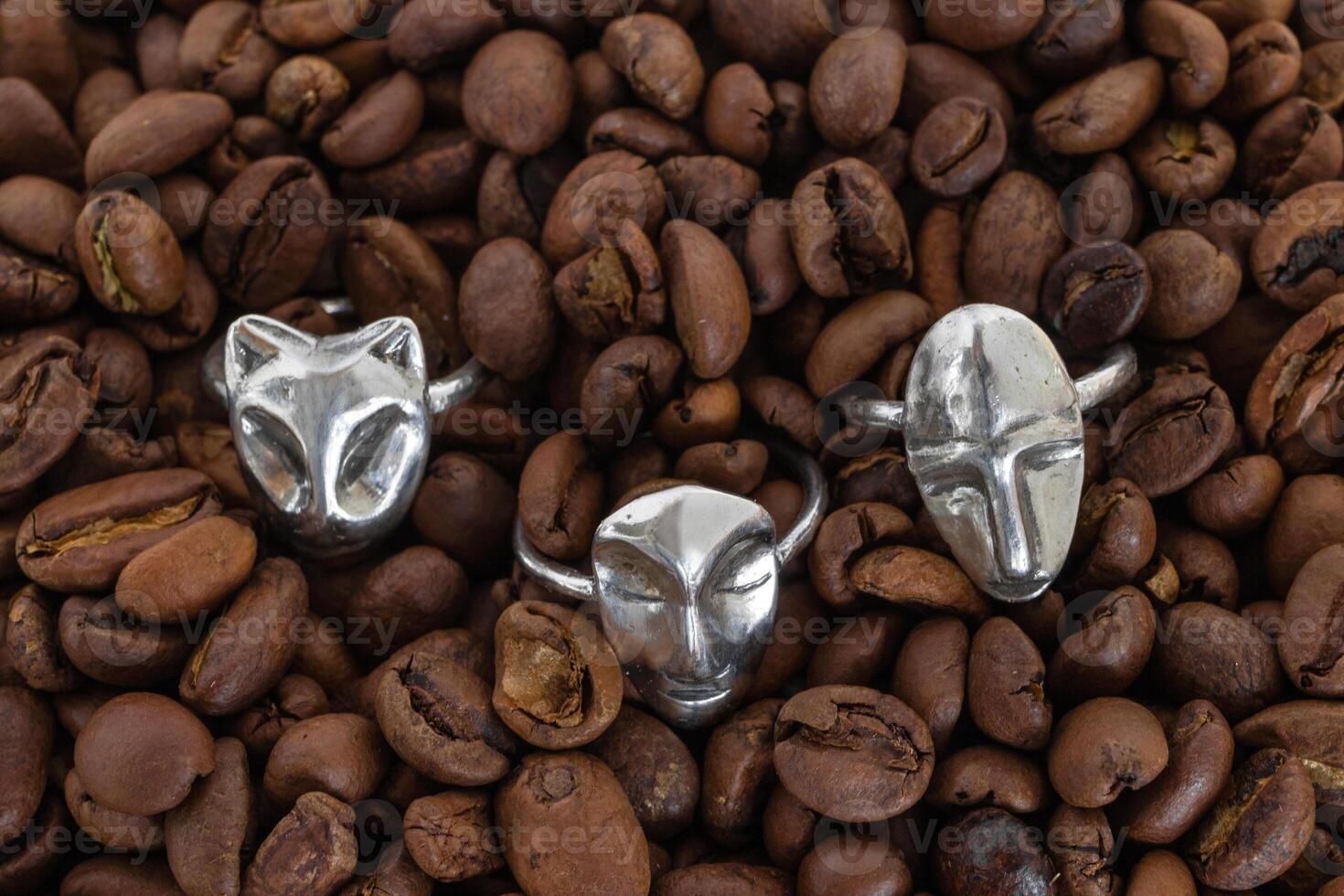 Collection of elegant silver rings on a background of coffee beans, top view. Handcraft precious item. Jewelry accessories. photo