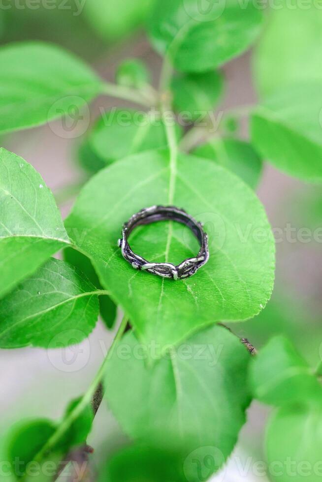 Beautiful silver handmade ring on a leaf of apple tree. Handcraft precious item. Jewelry accessories. photo