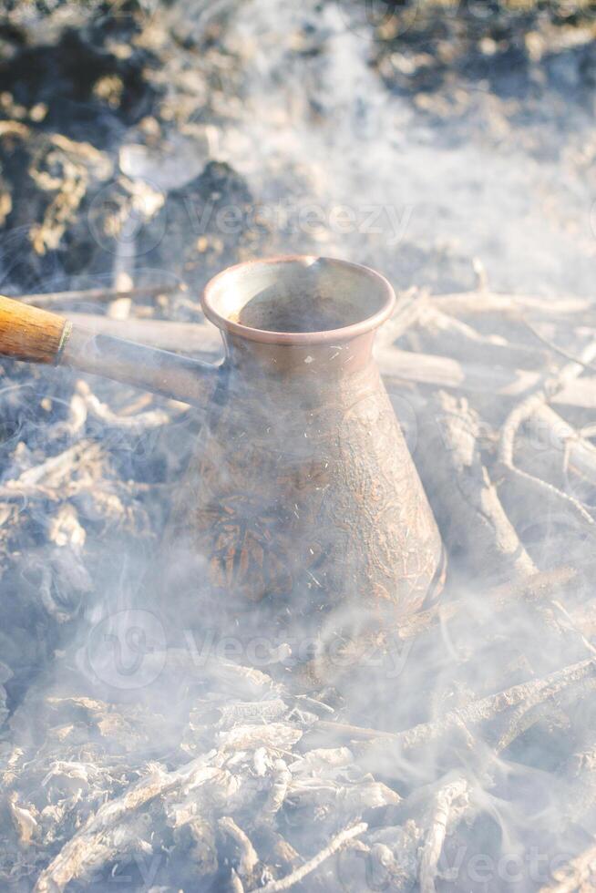 Boiling coffee in turkish cezva on campfire coals. photo